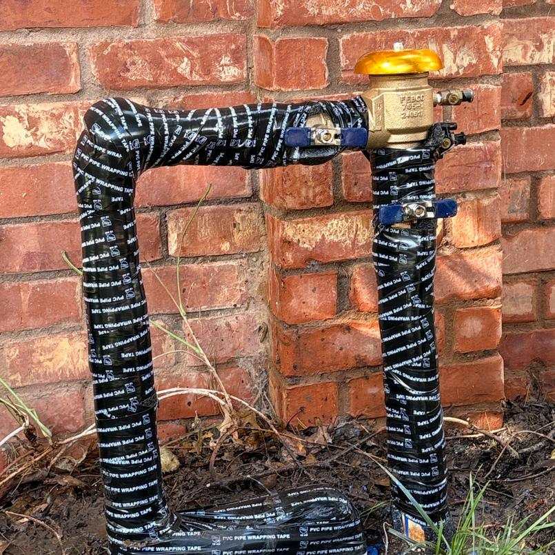 Wrapped backflow assembly against a brick wall